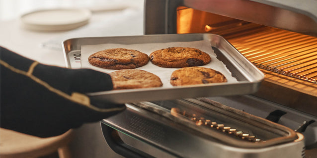 Person taking a tray of cookies out of the Ooni Volt 2 Pizza Oven