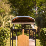 Ooni Koda 2 max gas pizza oven in a garden setting on top of the Ooni Large modular table.