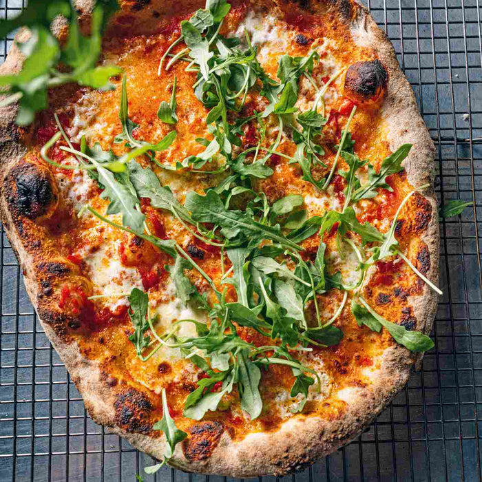 Pizza covered in arugula cheese and tomato