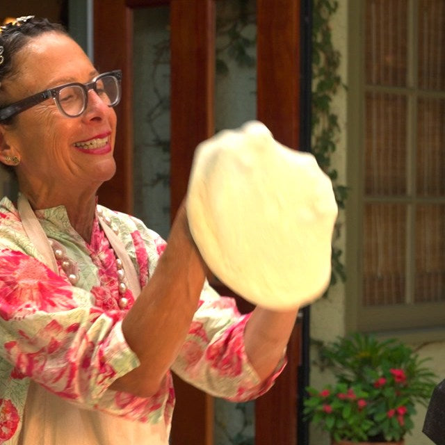 Nancy Silverton stretching pizza dough next to an Ooni pizza oven.