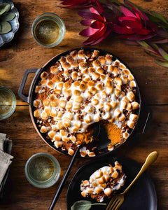 Cast iron pan filled with a marshmallow and pecan-topped sweet potato casserole