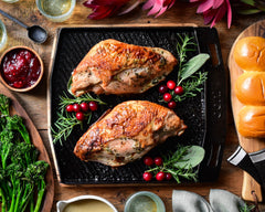 Two grilled turkey breasts in a cast iron pan with jalapeno, ginger and cranberry sauce