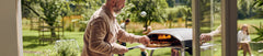 An image of the Koda 2 pizza oven and pizza peels on an orange background