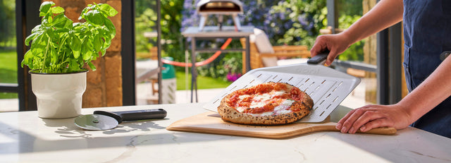 The Ooni Koda 2 oven, turning peel and metal peel on an orange background