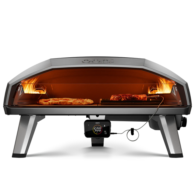 Front view of the Ooni Koda 2 max gas pizza oven with pizza and grizzler pan cooking meat side by side  