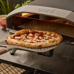 Ooni pizza oven with a freshly baked pizza on a signature pizza peel.