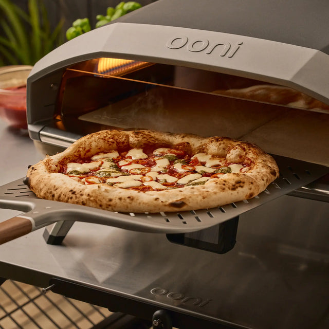 Ooni pizza oven with a freshly baked pizza on a signature pizza peel.