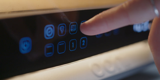 Hand pressing a button on the Ooni Volt 2 with illuminated buttons