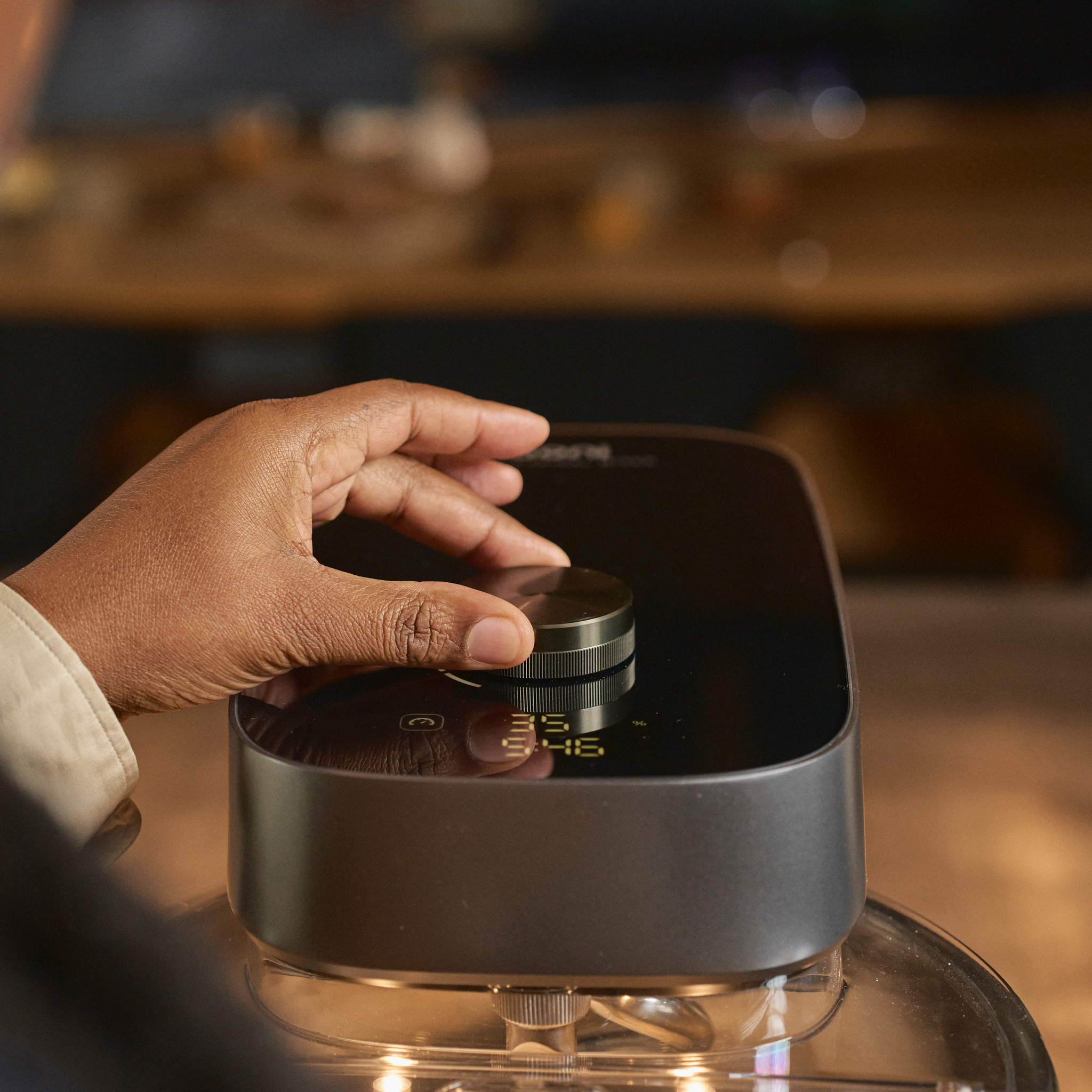 Hand adjusting digital scale on the Ooni Halo Pro Spiral Mixer with a blurred background
