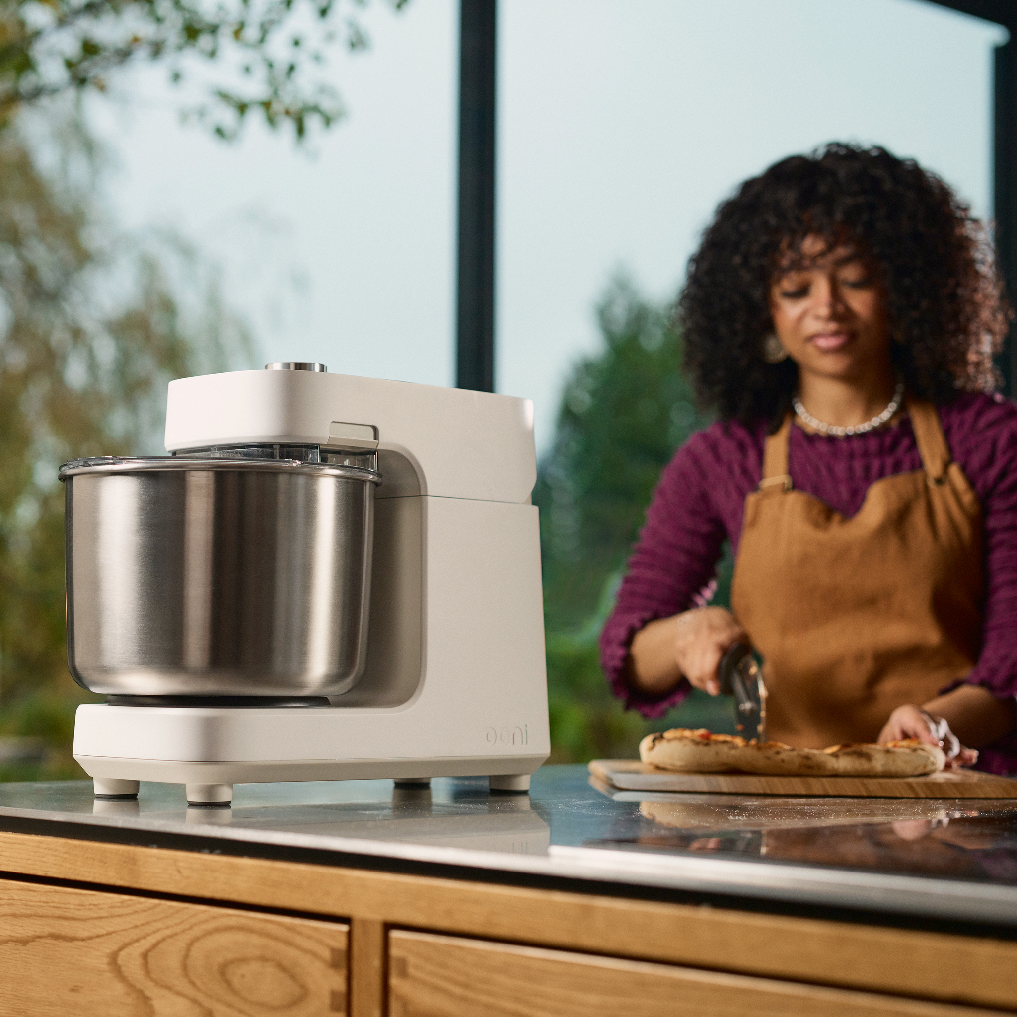 Ooni Halo Pro Spiral Mixer on a kitchen counter with a person in the background preparing food.