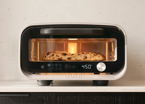 The Volt 2 oven on a kitchen counter with a pizza cooking inside.