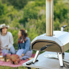 Outdoor pizza oven with people sitting on a blanket in the background