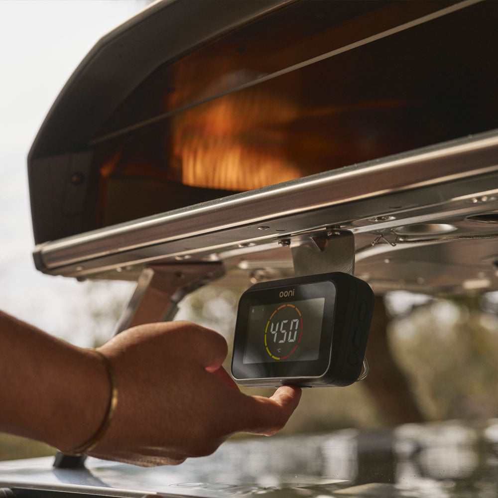 Hand holding a digital thermometer under the Koda 2 Pro oven.