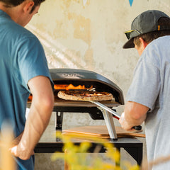 A man turns a cooking pizza in the Koda 16 using the Turning Pizza Peel