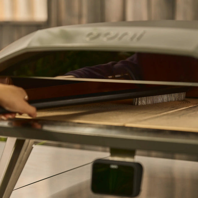 Person using the Ooni Pizza Oven Brush in the Koda 2 Max