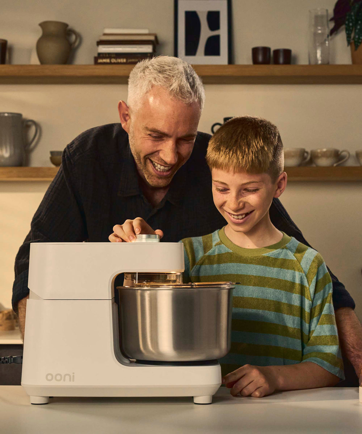 A father and son using the Halo Core spiral mixer with a kitchen blurred in the background.