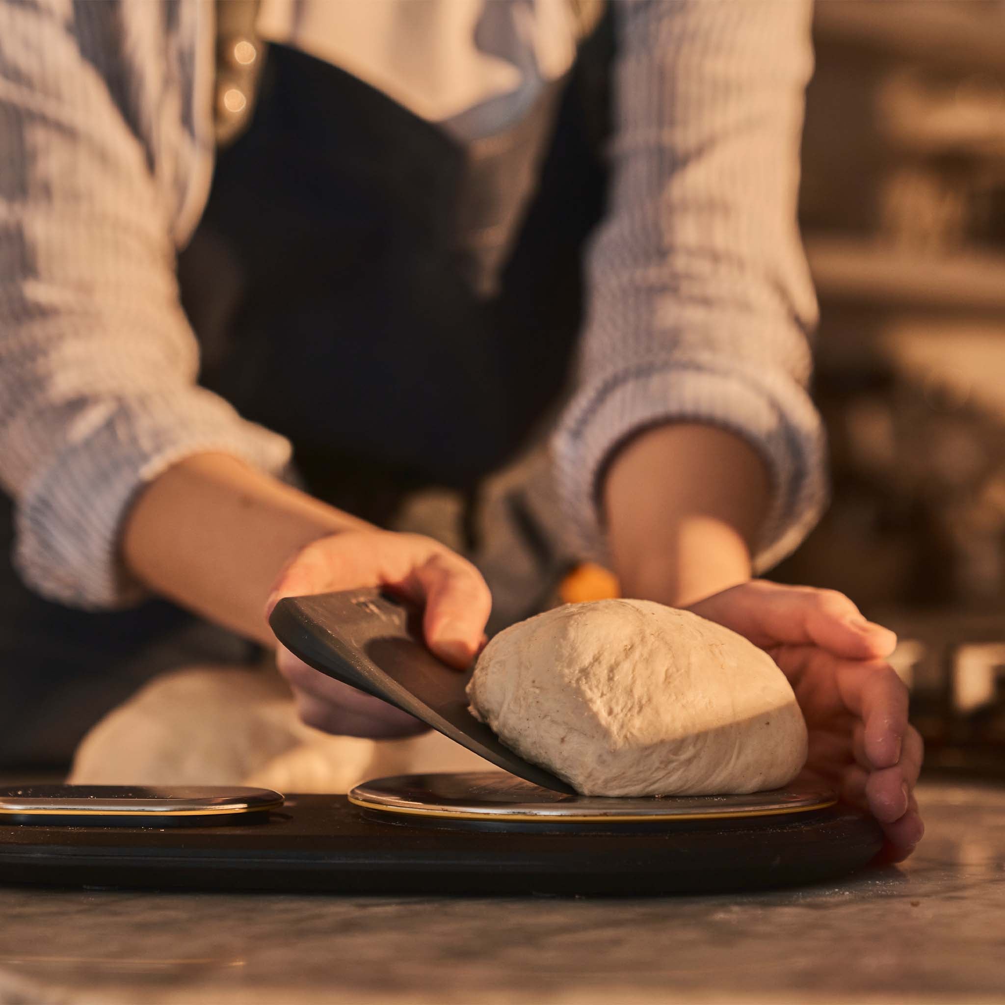 Ooni dough bench scraper lifting dough ball from digital measuring scales