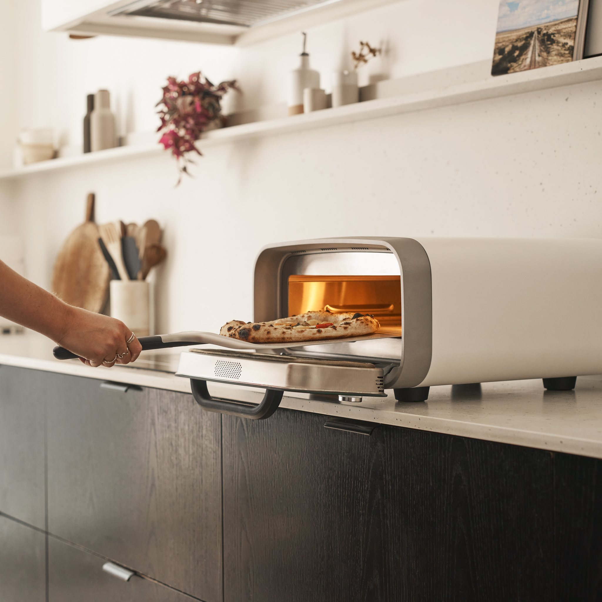 Person taking a pizza out of the Polar White Volt 2 Electric Pizza Oven.